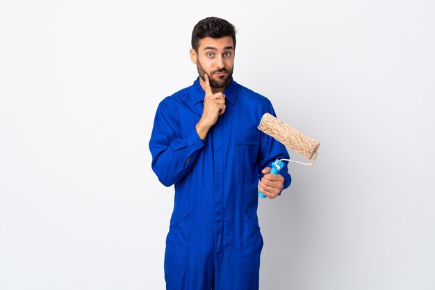 Painter man holding a paint roller isolated on white wall and thinking