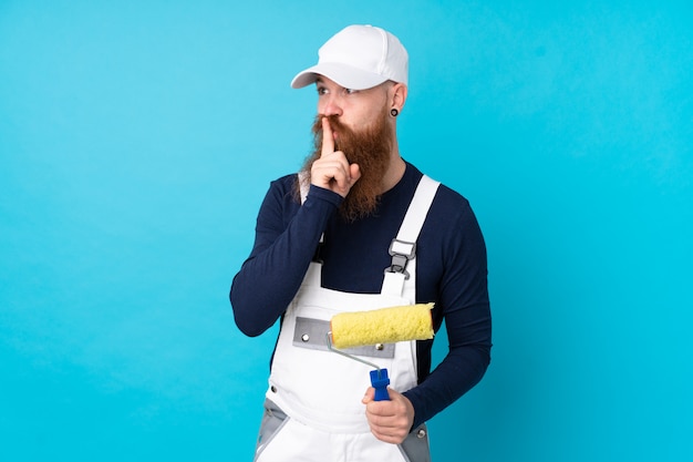 Painter man with long beard over isolated blue wall doing silence gesture