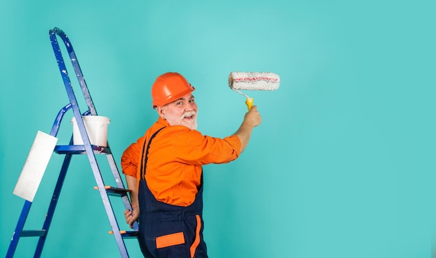 Photo painter in overall and cap with paint bucket. builder worker painting facade. thermal insulation works. painter man staircase. to make repairs. man in working clothes painting wall in empty room.