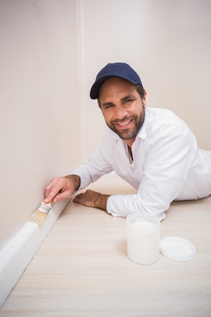 画家が新しい家に木製の板を描く