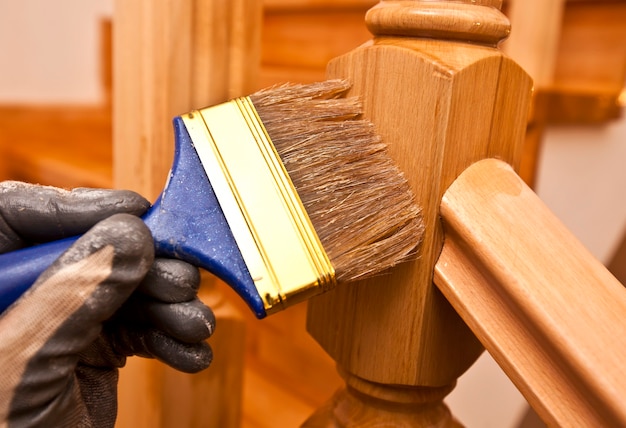 Painter paints a varnish wooden board by brush