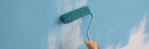 페인터는 롤러로 벽을 파란색으로 칠합니다. 집 개조와 장식 집 리노베이션