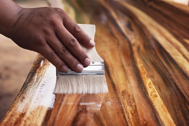 Painter uses paint plots to coat wood for beauty.