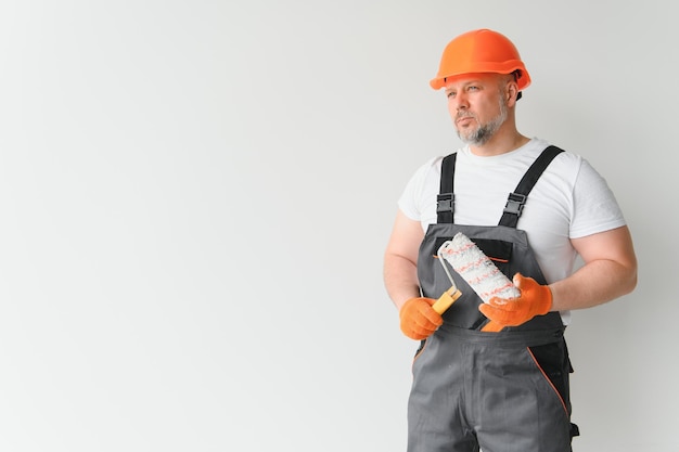 Painter using a paint roller and painting a wall isolated on white background