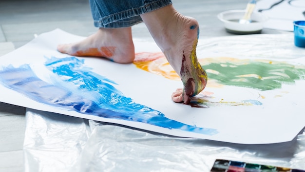 Painting art school. Closeup of artist feet walking on paper, creating colorful abstract artwork.