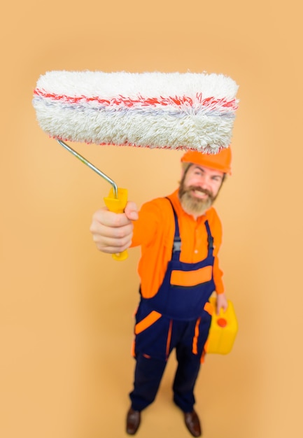 Painting concept bearded man in working clothes with paint\
roller bearded repairman in uniform hold