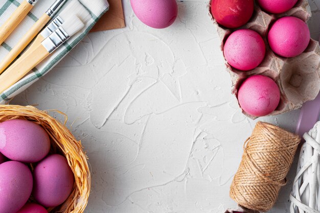 Painting Easter eggs in pink on white table, view from above