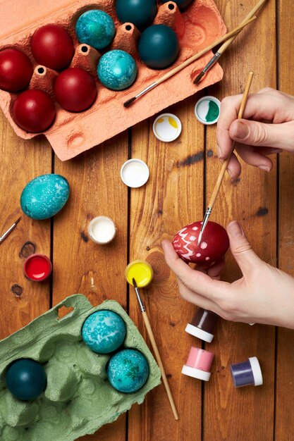 Painting eggs. Woman painting Easter eggs with painting brush. Preparing for Easter. Top view.