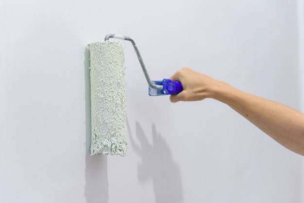 Painting out a white wall with a paint roller with white paint.