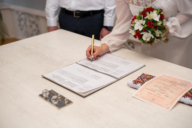 Painting in the registry office at the wedding ceremony signing a document with a ballpoint pen