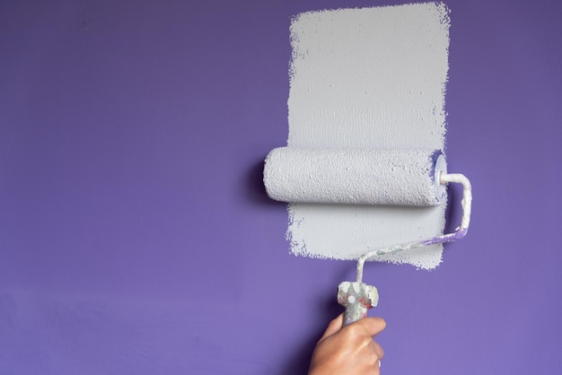 Photo painting roller applies light paint on dark wall and copy space for adding text or logo