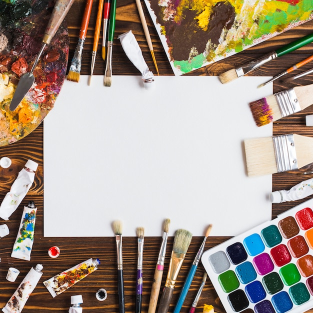 Painting supplies on table around paper