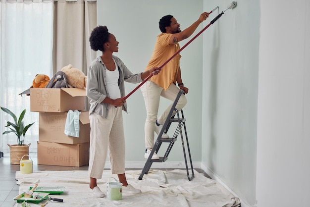 painting teamwork or black couple home renovation diy or house remodel together with paintbrush or roller happy smile woman and african man love working on wall with partnership or collaboration
