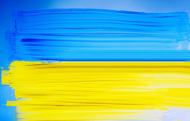 Photo painting ukraine flag on window ukraine flag brush concept color image of flag of ukraine on glass