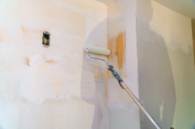 Painting walls, industrial worker using roller for painting