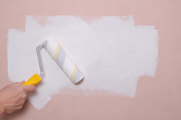 Painting the walls with a paint roller pink with white paint home repairs