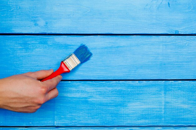 Painting on wood, hand with a brush, blue wood