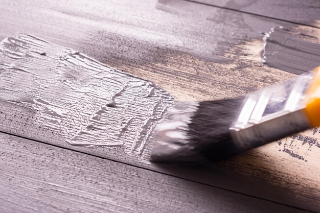 Painting a wooden surface with a brush and grayxA paint Natural wooden texture Renovation or repair construction