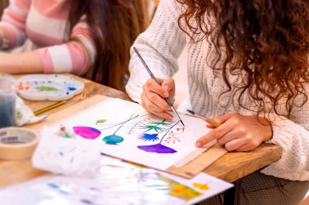 Painting Workshop Women paints picture on canvas with watercolor paints in her studio