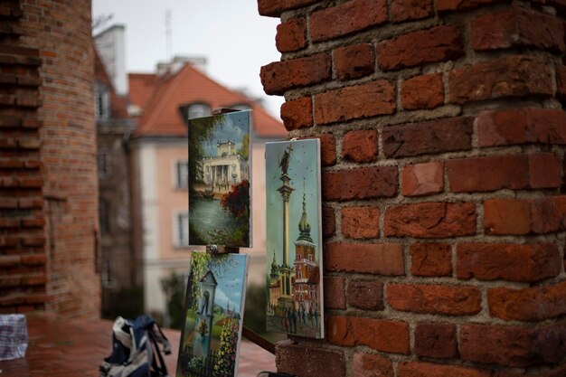 Paintings hanging on the wall representing Warsaw Street artist Brick wall