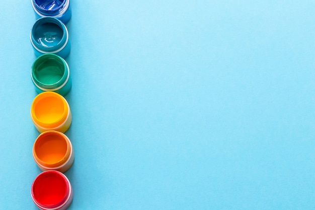 Photo paints in jars in row on blue background in top view