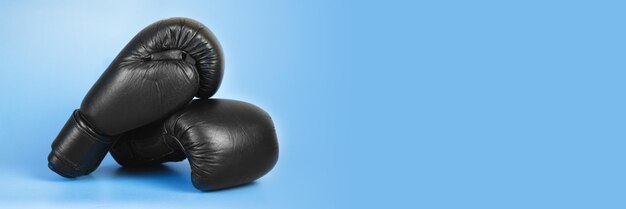 Pair of black leather boxing gloves on a blue background