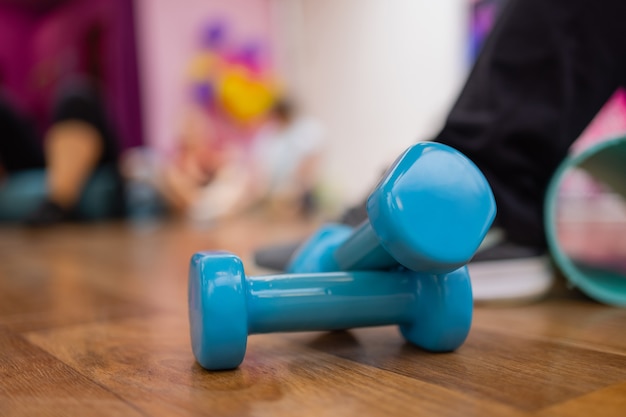 체육관이나 헬스 클럽의 고무 매트 바닥에 누워 있는 파란색 단단한 플라스틱 육각 덤벨 한 쌍.