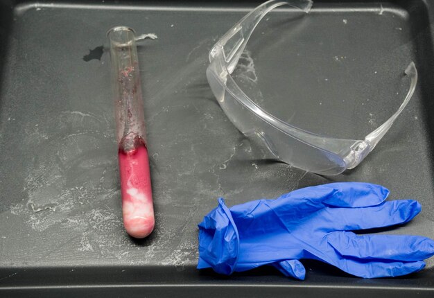 Pair of blue lab gloves protective goggles and flask bottle on laboratory