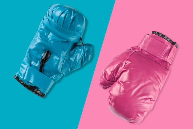 Pair of blue and pink boxing gloves on blue and pink background