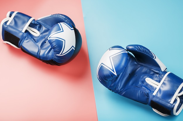 A pair of blue and pink boxing gloves on a blue and pink background.