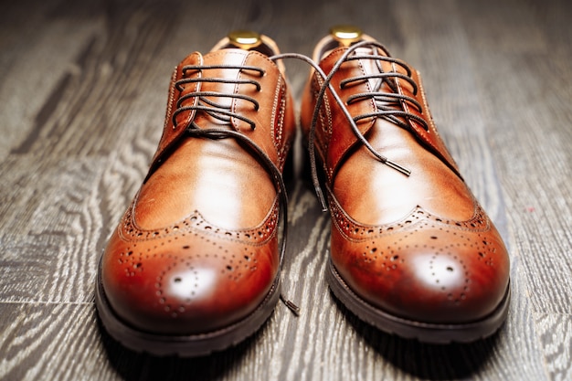 Pair of brown leather men's shoes on the wooden floor.