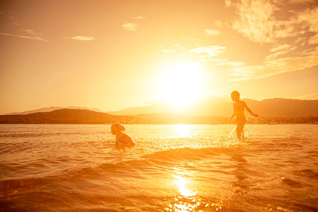 Pair of children playing in the sea, shot taken at sunset