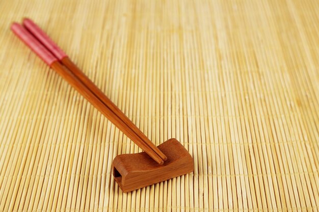 Photo pair of chopsticks on light bamboo mat background