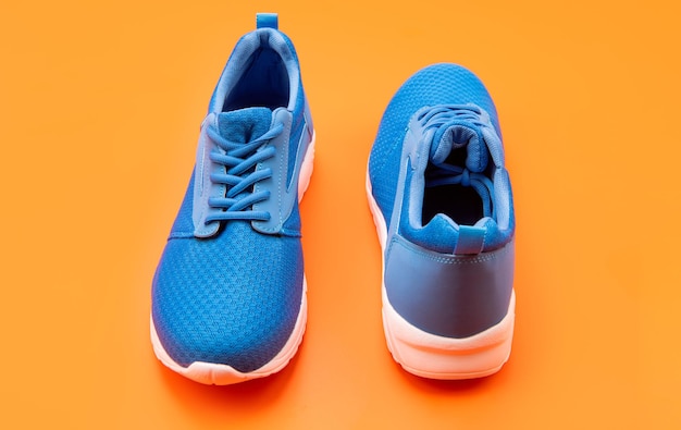 Pair of comfortable blue sport shoes on orange background fitness