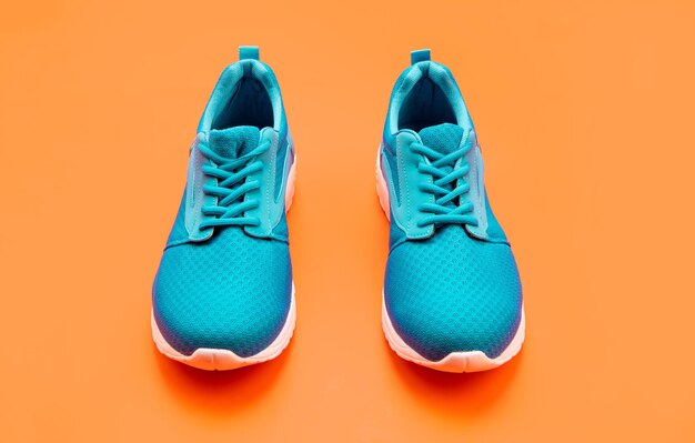Pair of comfortable blue sport shoes on orange background sport