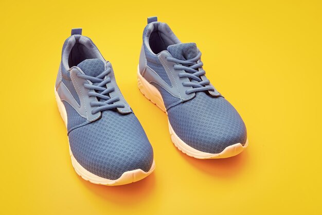 Pair of comfortable blue sport shoes on yellow background footwear