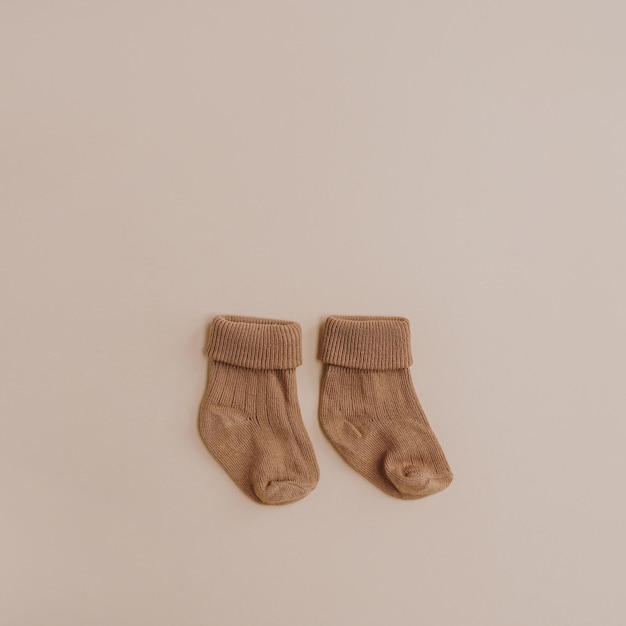 Пара уютных пастельных красочных носков для новорожденных на нейтральном бежевом фоне Эстетический минималистский коллаж детской моды Концепция счастливого материнства