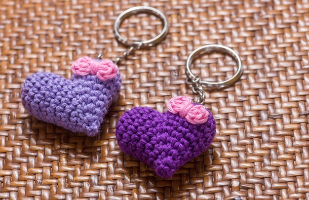 A pair of crocheted purple heartshaped keyrings on a brown textured background