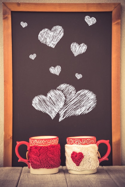 Pair of cups against blackboard background. Valentines day ornament. Greeting card