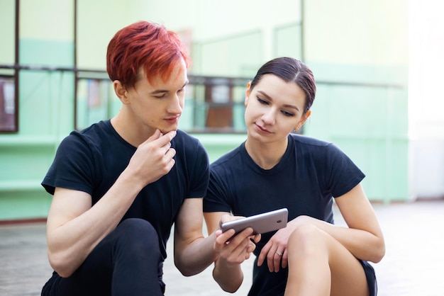 Pair of dancers watching video lesson of dancing on the phone. Online learning to dance, practicing from videos