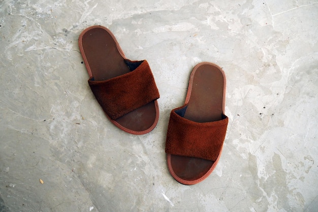 A pair of dirty and wet soft brown house slippers Top view of hotel bathroom slippers isolated on c