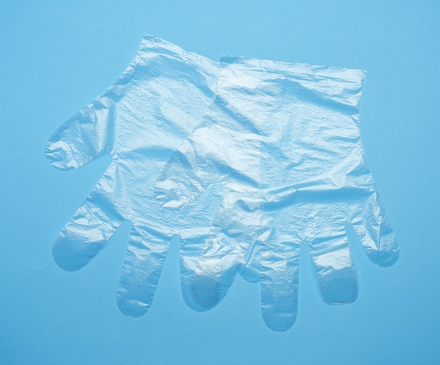 Pair of disposable polyethylene gloves on a blue background