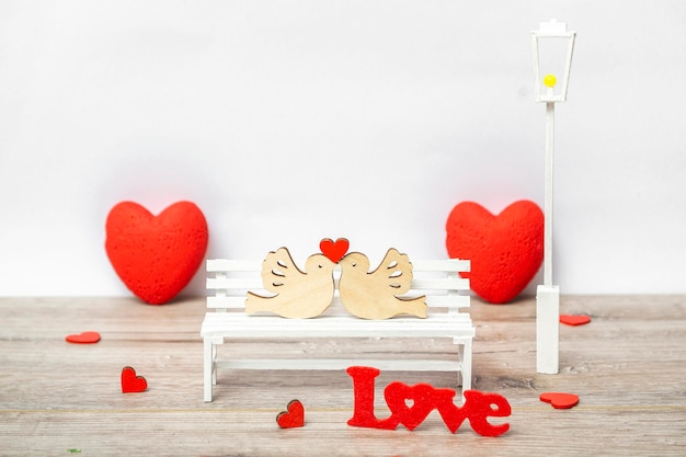 Una coppia di colombe con un cuore su una panchina bianca. concetto di amore, primo piano con spazio di copia.
