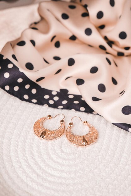 A pair of earrings on a bed with a polka dot background