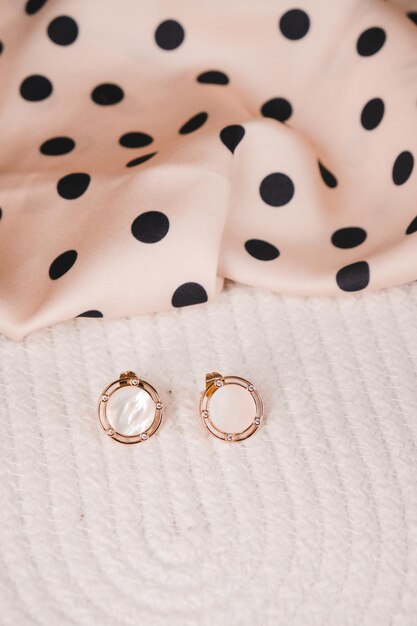 A pair of earrings with a black polka dot dress on the left.