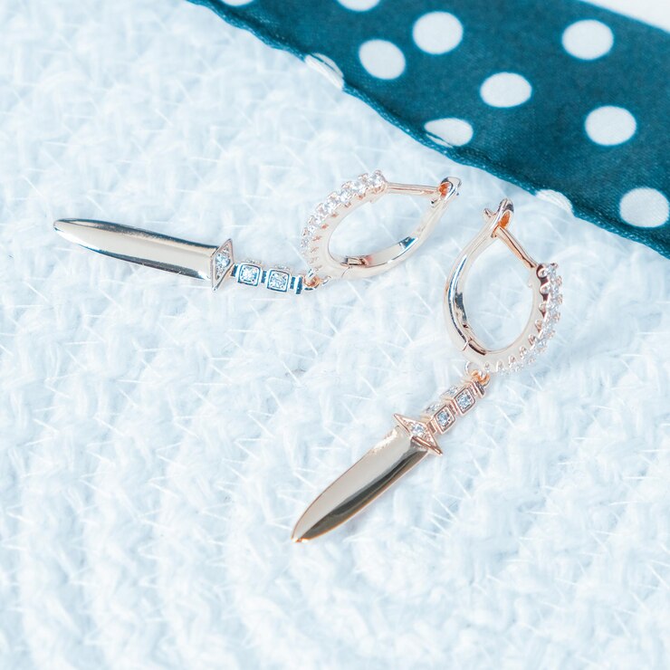 A pair of earrings with a blue ribbon and a white polka dot.