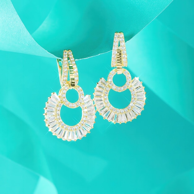 A pair of earrings with diamonds are hanging on a turquoise background.