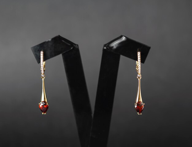 A pair of earrings with a red garnet stone on the top.