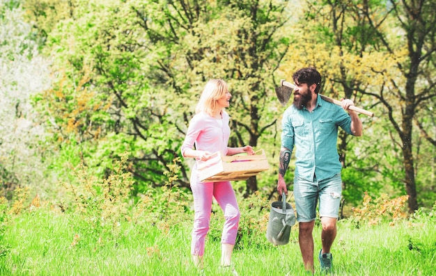 A pair of farms carries boxes with vegetables and greens along the field couple gardener portrait of