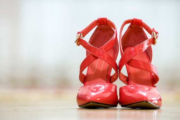 Pair of fashionable high heel leather red cut-out female shoes with golden buckles isolated on light copy space background. Style and fashion, modern footwear concept.